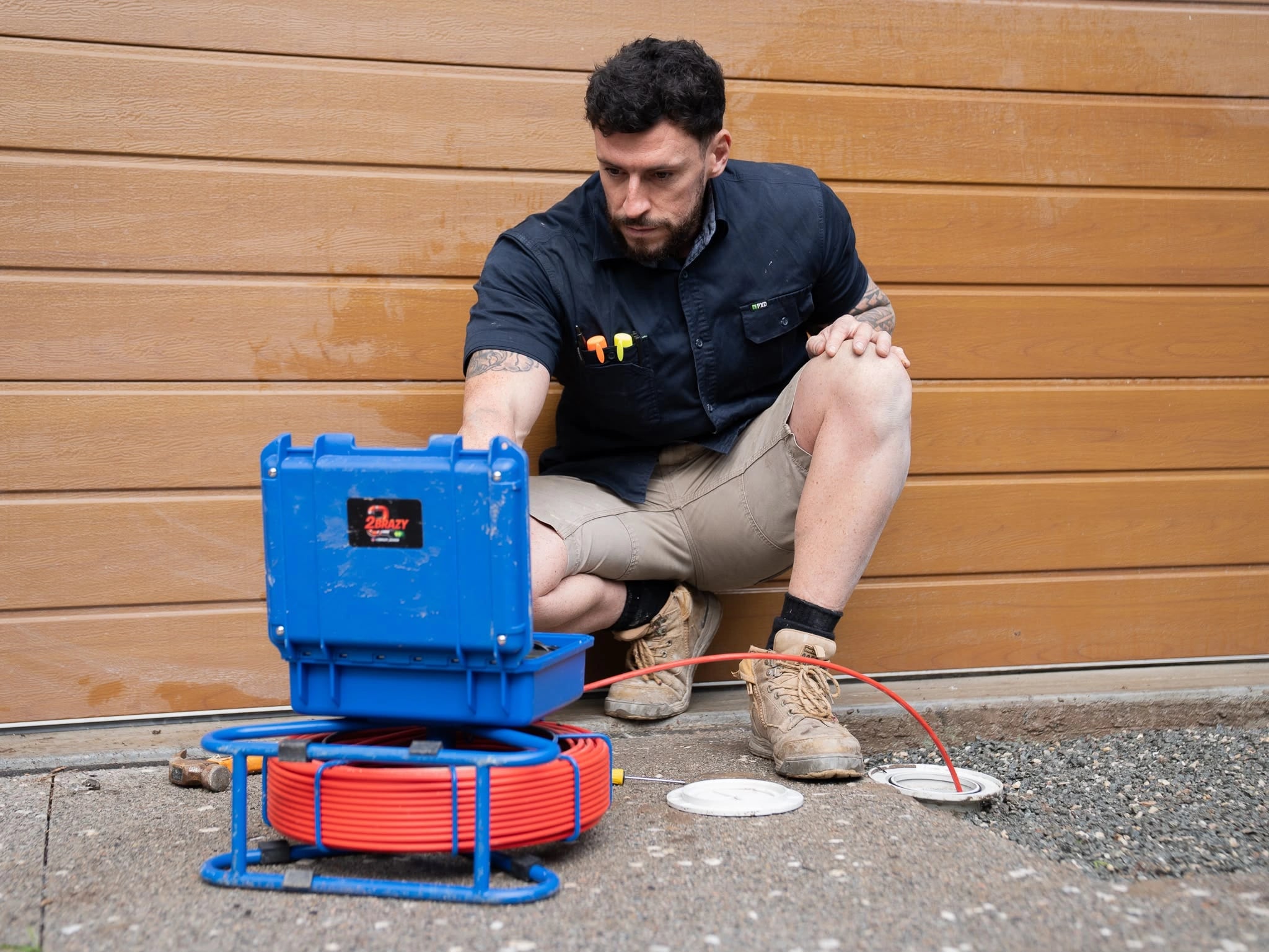 Tom Malone beside a blue drain inspection camera and cable reel